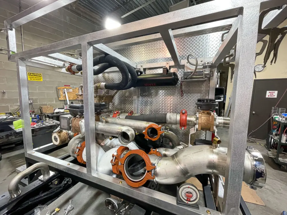 Exterior view of small fire truck showing cab, body compartments, and wheel/tire area.